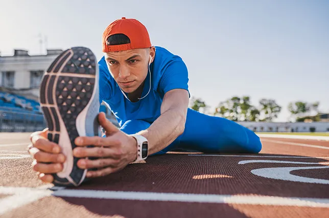 Image of runner stretching on track